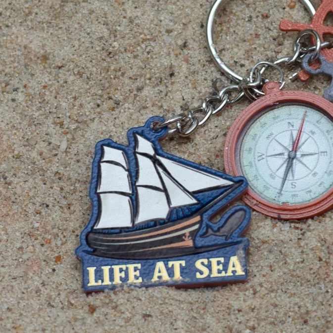 Flat 3D-printed promotional keychain shaped like a sailing ship with the words Life at Sea