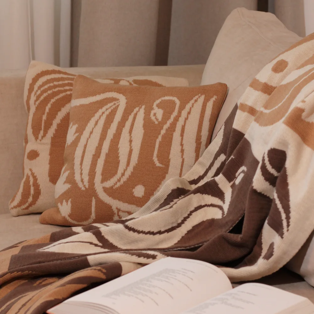 Dothat set – a knitted blanket and patterned pillow on a sofa