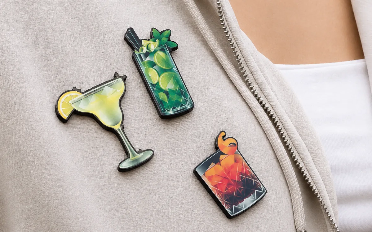 Trzy przypinki 3D w kształcie drinków przypięte do bluzy