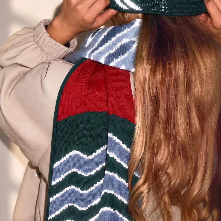 Reflective scarf with a green and blue wave pattern and a red stripe, thrown over the shoulder